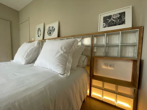 Chambre lumineuse aux Nomads Togo avec oreillers blancs, tête de lit en bois avec panneaux vitrés et tableaux encadrés