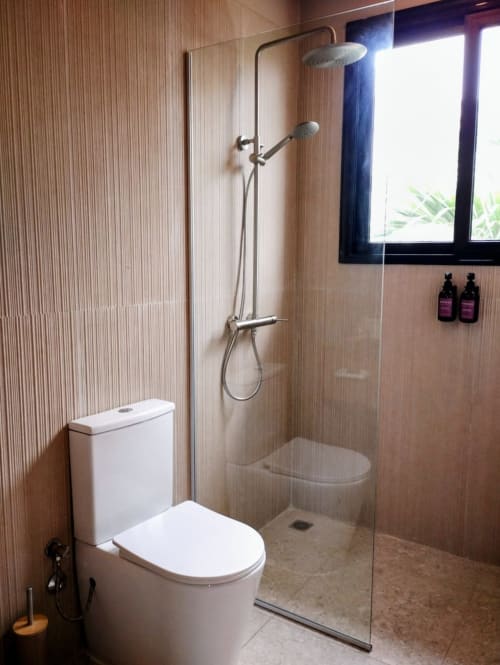 Salle de bains moderne avec douche ouverte, toilettes et équipements à Nomads Togo à Lomé