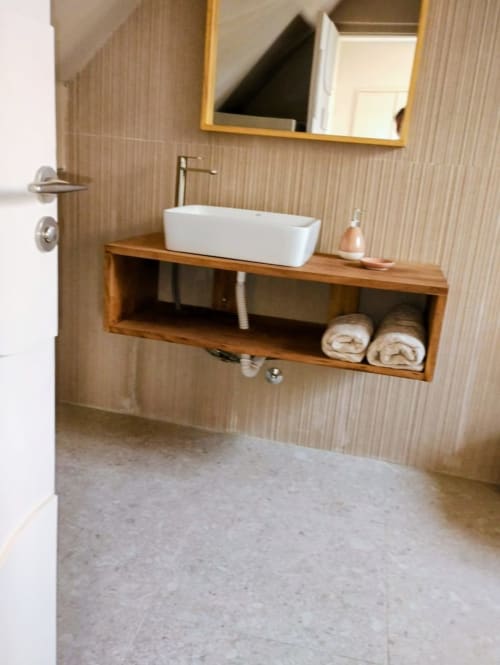 Lavabo moderne blanc rectangulaire, étagère en bois avec serviettes, miroir cadre doré à l'hôtel Nomads Togo