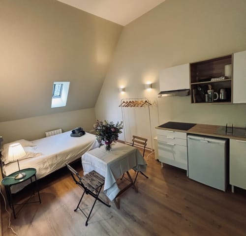Petit Studio du Manoir de Daubeuf : chambre mansardée douillette avec lit, kitchenette, coin repas et plafond pentu à Daubeuf-Serville
