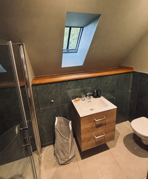 Salle de bain moderne du cottage Petit Studio au Manoir De Daubeuf avec vanité en bois, carrelage foncé, puits de lumière et douche