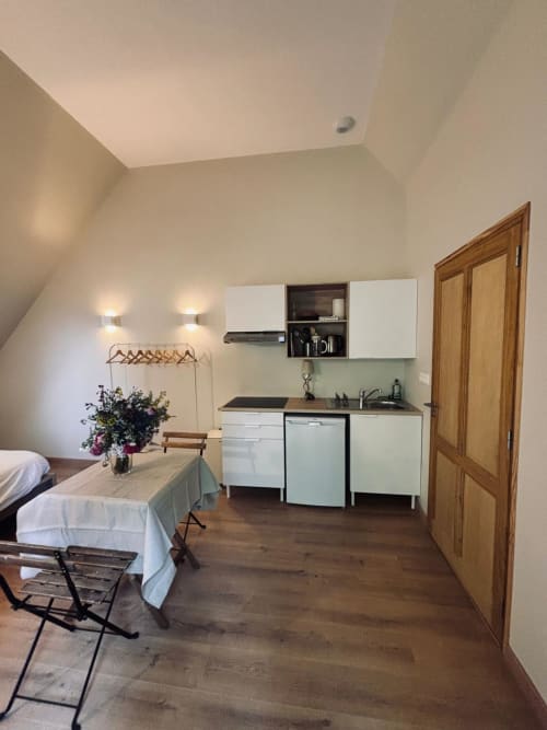 Chambre lumineuse au Manoir De Daubeuf avec kitchenette, lit, coin repas et portes en bois