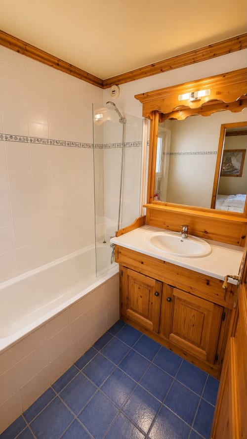 Modern bathroom with wooden vanity, white subway tiles, and blue floor at Le Chalet des Cimes, Belle Plagne