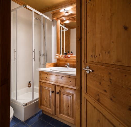Modern bathroom at Le Chalet des Cimes with wooden vanity, glass shower enclosure, and illuminated mirror in Belle Plagne