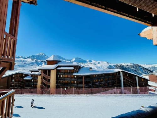 Le Chalet des Cimes à Belle Plagne avec montagnes enneigées et skieurs sur les pentes