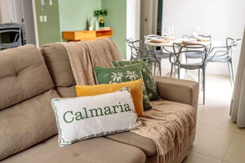 Sofá bege com almofadas decorativas, incluindo almofada 'Calmaria' no apartamento Villa Dell'Acqua, Canasvieiras, Florianópolis