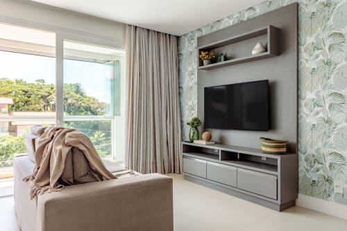 Sala de estar em apartamento à beira-mar com TV na parede, papel de parede tropical, varanda com vista para o mar e design contemporâneo
