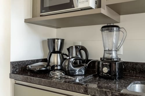 Bancada da cozinha com liquidificador, cafeteira, chaleira e eletrodomésticos no apartamento Sua Estadia, Florianópolis