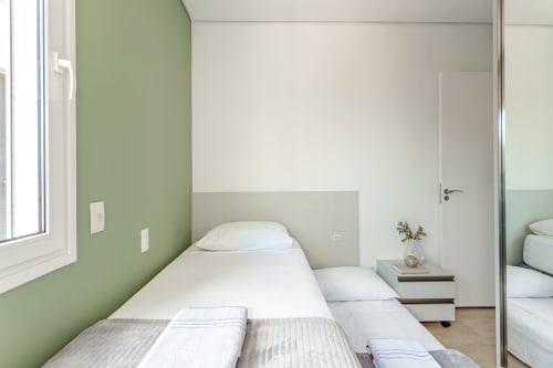 Quarto moderno no apartamento Villa Dell'Acqua, Canasvieiras, Florianópolis com camas gêmeas, parede verde e vista para a praia