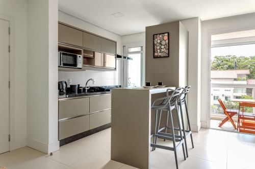 Cozinha moderna e sala de jantar em apartamento à beira-mar com bar, eletrodomésticos em aço inoxidável e vista para o oceano