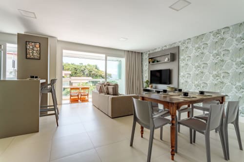 Moderno apartamento à beira-mar em Canasvieiras com sala de estar aberta, mesa de jantar, vista para o mar e acesso à varanda