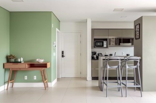 Cozinha e sala de estar modernas em Canasvieiras, Florianópolis com parede de destaque verde, balcão de refeições e