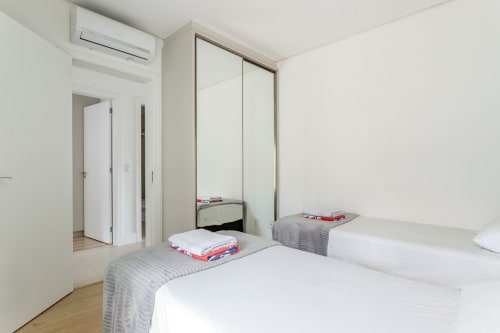 Quarto moderno do apartamento Villa Dell'Acqua em Canasvieiras, Florianópolis com camas gêmeas e guarda-roupa espelhado