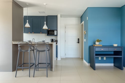 Cozinha e sala de estar modernas no apartamento Villa Dell'Acqua com paredes azuis, eletrodomésticos em aço inoxidável, bar e