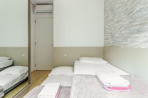 Quarto moderno com camas individuais em apartamento frente mar em Canasvieiras, Florianópolis, vista para o mar, ar-condicionado split e piso de madeira