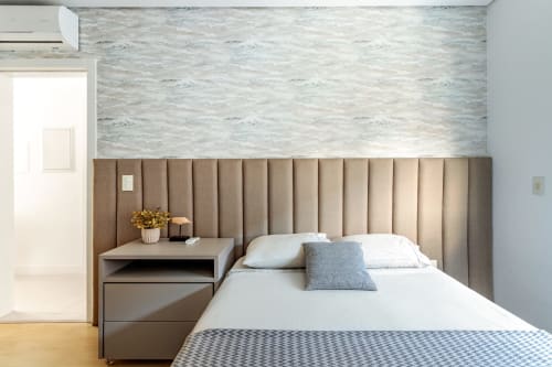 Cabeceira estofada em tons neutros com roupa de cama branca e almofada azul no apartamento Villa Dell'Acqua, Canasvieiras