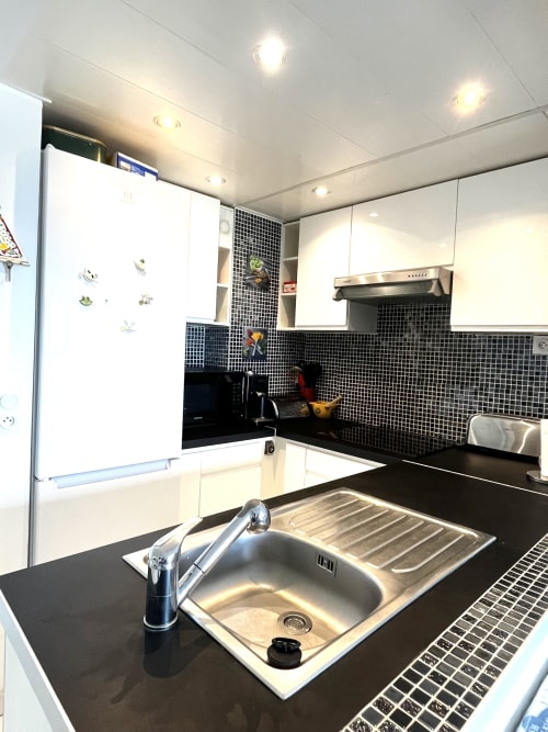 Cuisine moderne avec dosseret en mosaïque noire, armoires blanches, évier et robinetterie en acier inoxydable à l'appartement Barcaresa au Port