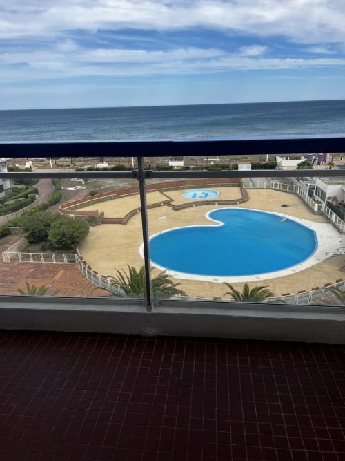 Vue depuis le balcon du Port Leucate Barcaresa avec piscine réniforme bleue, cour de sable et horizon marin sous ciel bleu