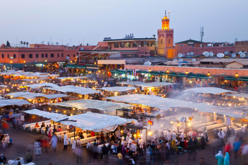 Place Jemaa el-Fnaa à Marrakech au crépuscule avec étals illuminés et mosquée