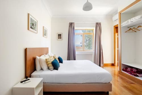 Modern bedroom at Voluta Management BnB in Chaves with wooden bed, white linens, and bay window