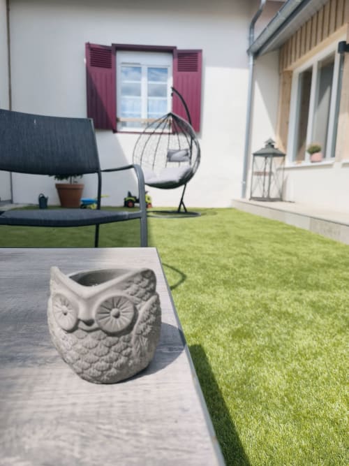 Patio cosy du Domaine de Castagnère avec jardinière chouette décorative, chaise suspendue et vue sur la campagne française