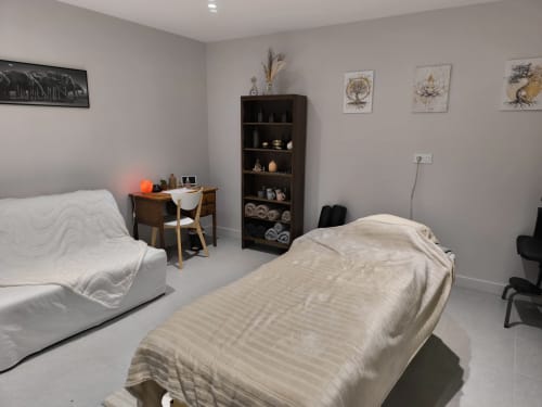 Salle de soins spa moderne au Domaine de Castagnère avec lits de massage, étagères en bois et décoration épurée