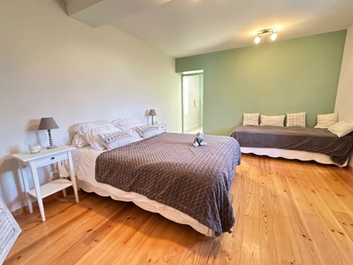 Chambre spacieuse du Domaine de Castagnère avec lit double, mur d'accent vert, parquet et coin détente