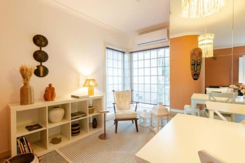 Bright modern bedroom in Chaves BnB with orange accent wall, shelving unit, and large windows overlooking the city