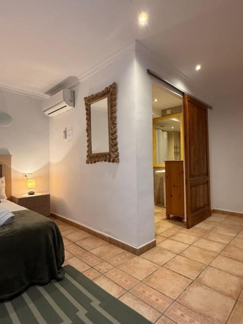 Habitación moderna en Hotelito Oliva Pensión en Oliva con paredes blancas, espejo ornamentado, puerta de baño de madera y azulejos