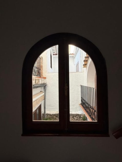 Puertas dobles arqueadas en negro con cristales que abren a la vista del patio del Hotelito Oliva Pensión en Oliva, España