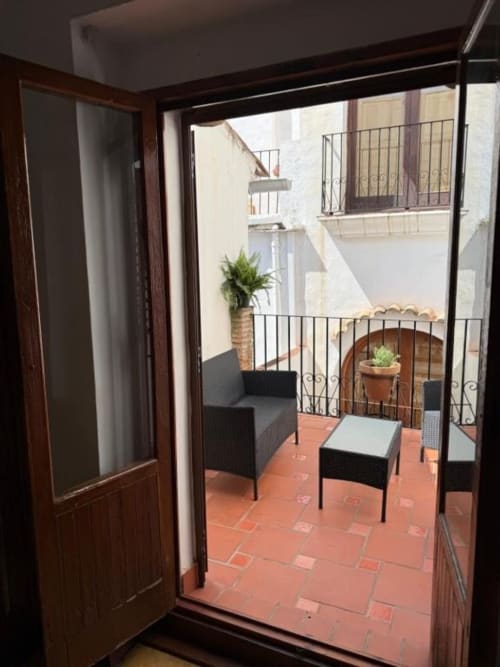 Vista del balcón en Hotelito Oliva Pensión en Oliva, España con muebles de mimbre negro y baldosas de terracota