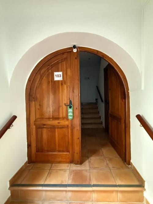 Puerta arqueada de madera numerada 103 en Hotelito Oliva Pensión en Oliva, España, que conduce a la escalera interior