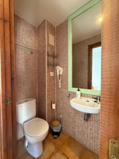 Baño moderno del Hotelito Oliva con azulejos de mosaico marrón, lavabo blanco, inodoro y ducha en Oliva, España