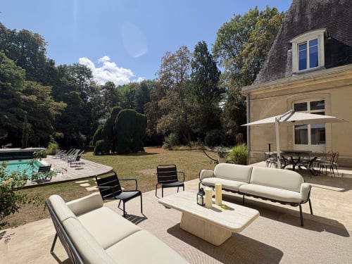 Terrasse élégante du château d'Hermonville avec salon, vue sur la piscine et jardins soignés