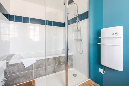 Salle de bain moderne chez Dupain & Dubeurre à Limoges avec douche à l'italienne, mur d'accent bleu et sèche-serviettes électrique