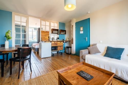 Appartement studio lumineux à la chambre d'hôtes Dupain & Dubeurre à Limoges avec accents turquoise, parquet, kitchenette et canapé
