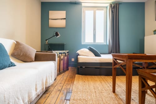 Chambre lumineuse avec lits jumeaux, murs bleu-vert, parquet et vue sur le jardin chez Dupain & Dubeurre Limoges