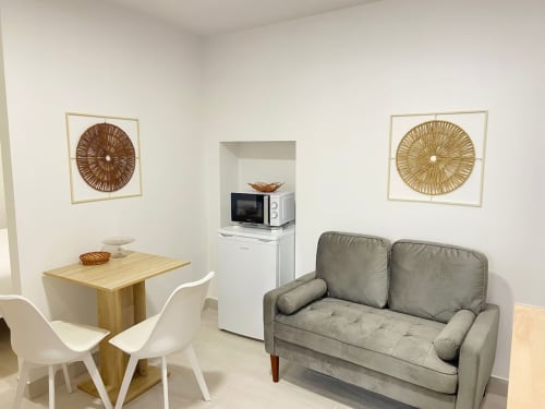 Moderna sala de estar no Casa das 7 Janelas, Peniche, com sofá cinzento, mesa de jantar e kitchenette