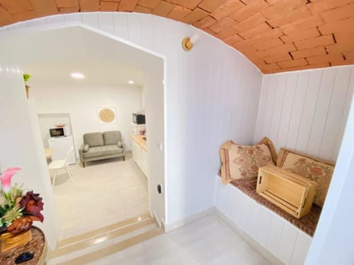 Apartamento Casa das 7 Janelas em Peniche com sala, alcova do quarto, paredes brancas e teto de madeira