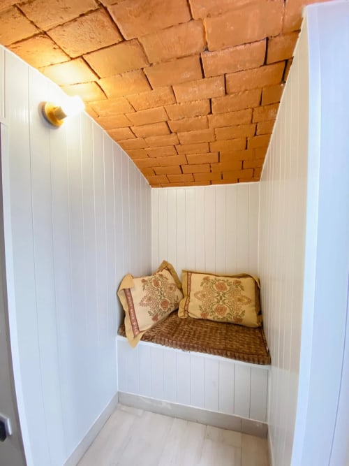 Quarto aconchegante em nicho na Casa das 7 Janelas em Peniche com teto de tijolos, paredes brancas e almofadas decorativas