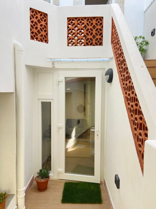 Entrada moderna do apartamento em Casa das 7 Janelas em Peniche com porta branca, azulejos de terracota e decoração verde