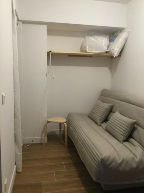 Chambre compacte de l'appartement GNM à Vars avec lit futon, tabouret bois, étagères murales et parquet