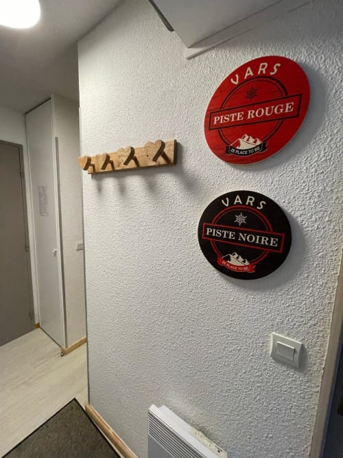 Couloir d'appartement à Vars avec panneautage de piste de ski et décoration de skis en bois sur mur texturé