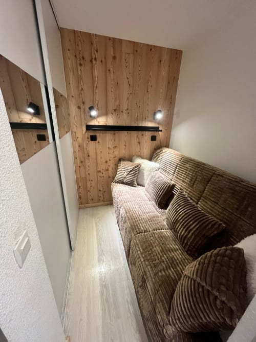 Chambre confortable de l'appartement GNM à Vars : mur en bois, éclairage ambiant, literie rayée, design moderne compact pour 4-5 personnes