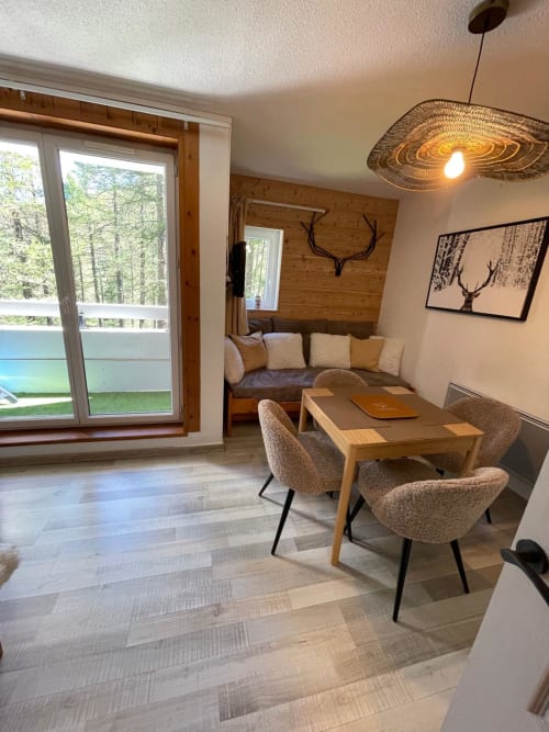 Séjour moderne à GNM Vars avec table à manger, coin détente et vue sur la forêt