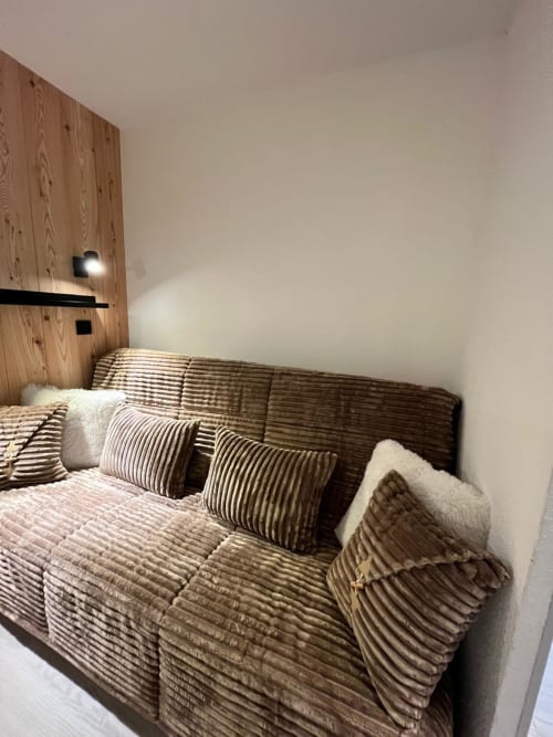 Chambre moderne dans l'appartement de Vars avec lit rayé, tête de lit en bois et coussins décoratifs