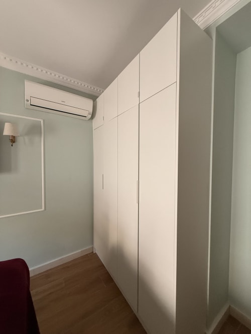 Dormitorio moderno con armario blanco empotrado, aire acondicionado y suelo de madera en apartamento de Sevilla