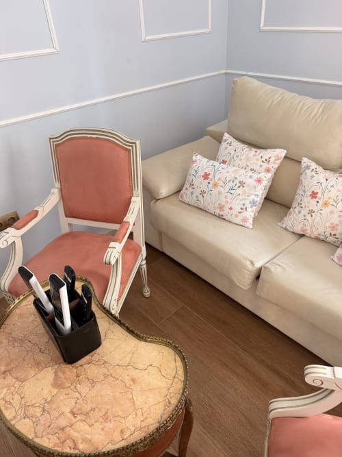 Elegante sala de suite con sofá color crema, cojines florales, silla coral y mesa de mármol redonda en Edificio San Esteban