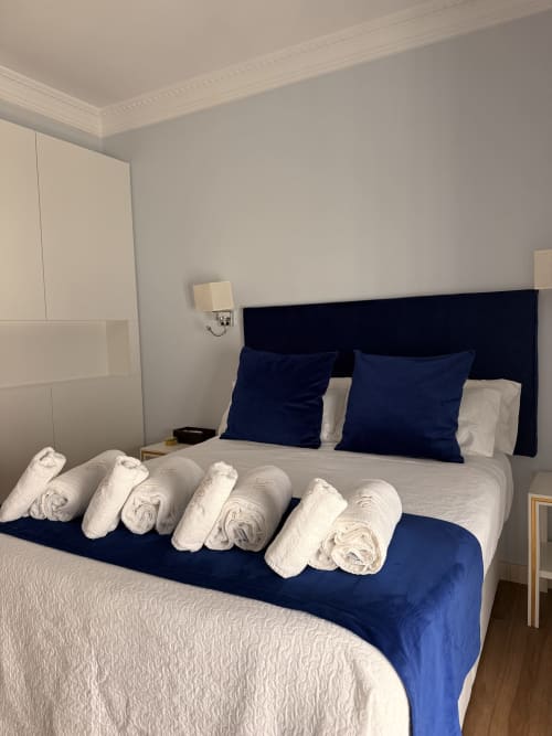 Suite dormitorio en Edificio San Esteban 16 de Sevilla con toallas blancas enrolladas en el camino de cama azul marino y almohadas azules