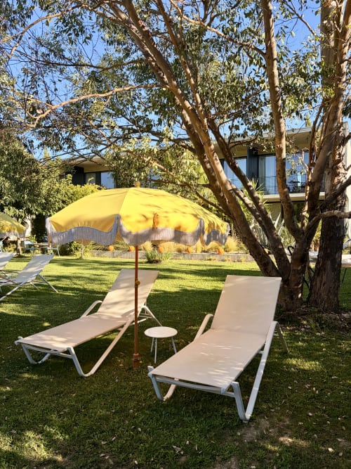 Terrasse ensoleillée de la Maison Jalon avec transats blancs sous parasol jaune et eucalyptus, Aix-en-Provence
